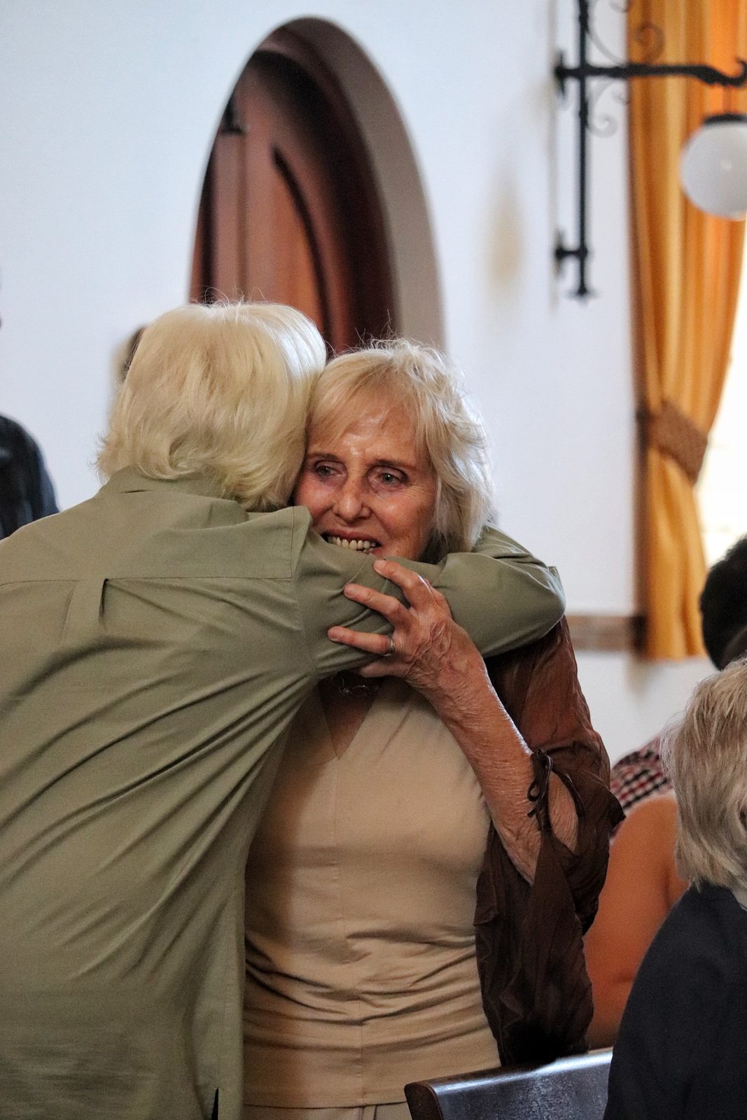 Twee lidmate omhels mekaar by die erediens